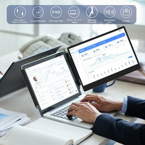 Person using a dual-screen laptop setup with graphs and charts displayed.