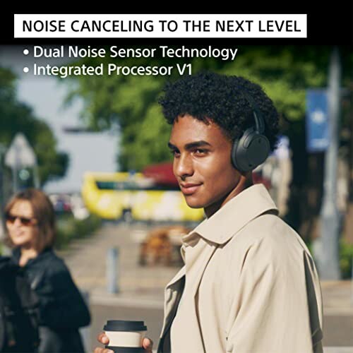 Person wearing noise-canceling headphones outdoors with text about dual noise sensor technology.